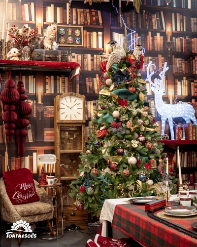 Sapin décoré rouge et or devant une bibliothèque, chouettes, renne lumineux et table tartan du thème Christmas Tale